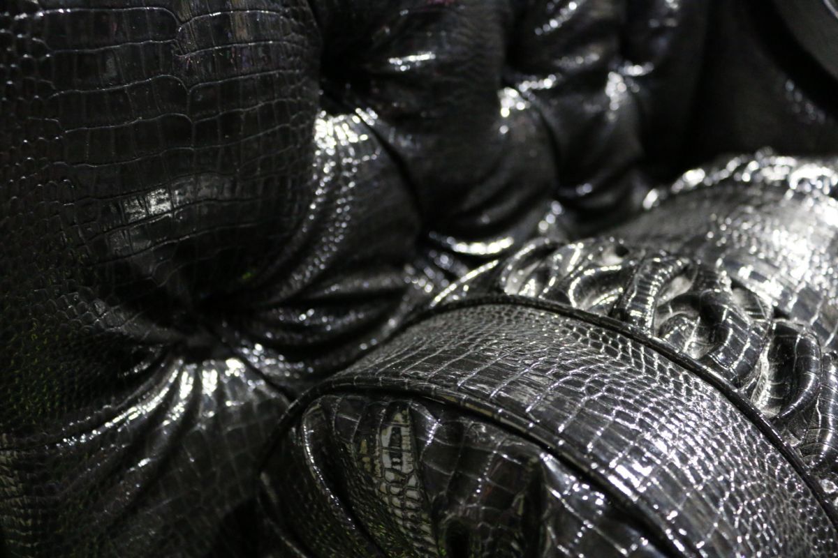 Close-up of glossy black faux-crocodile upholstery crafted by Reveal Productions, showing detailed tufting used in Moulin Rouge’s stage furniture.