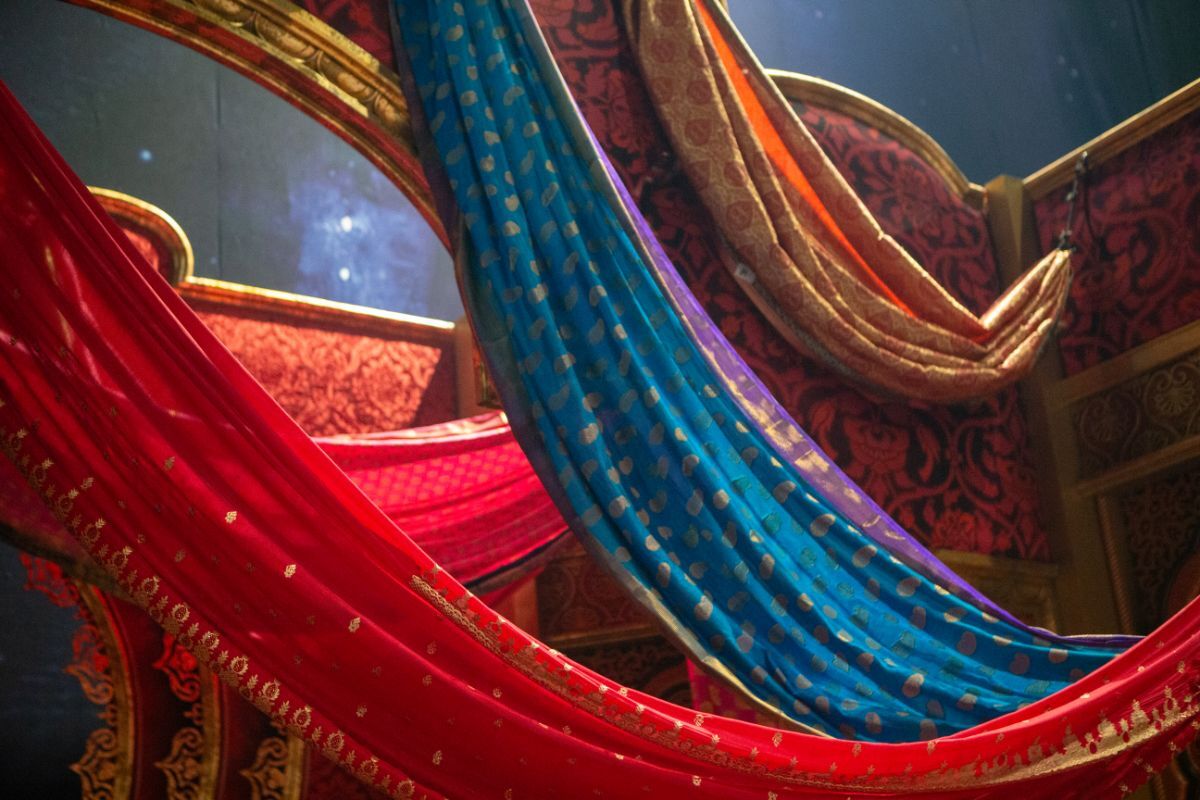 Red, blue, and gold silk drapes with metallic detailing created by Reveal Productions, showcasing the rich theatrical fabrics used in Moulin Rouge.