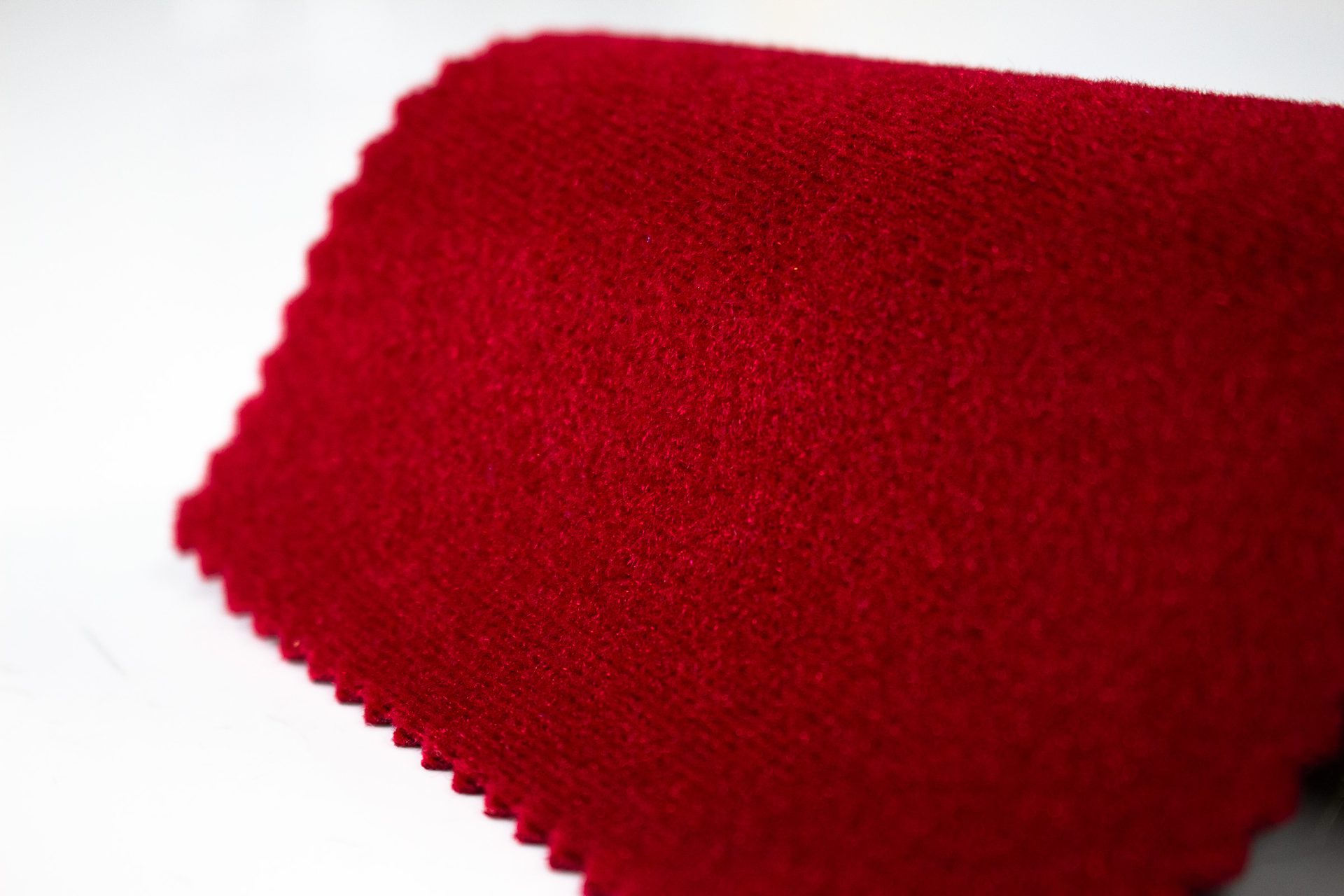 Close-up of ruby red Ultra Velvet stage fabric with a pinked swatch edge