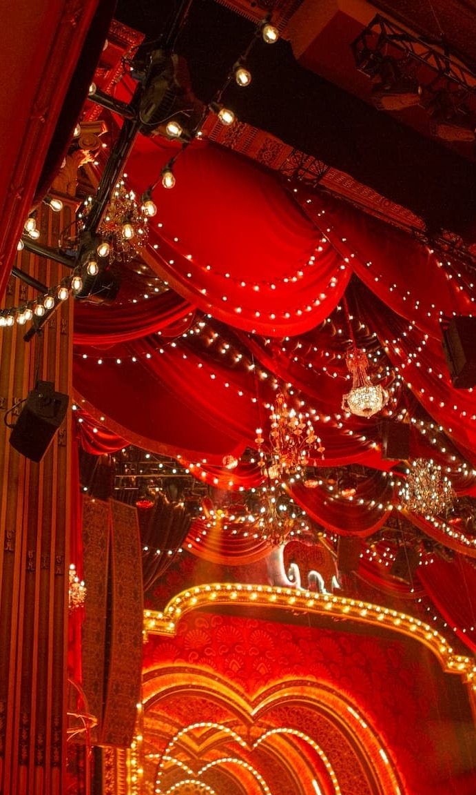 Red velvet drapery and chandeliers forming the auditorium ceiling design for Moulin Rouge! The Musical