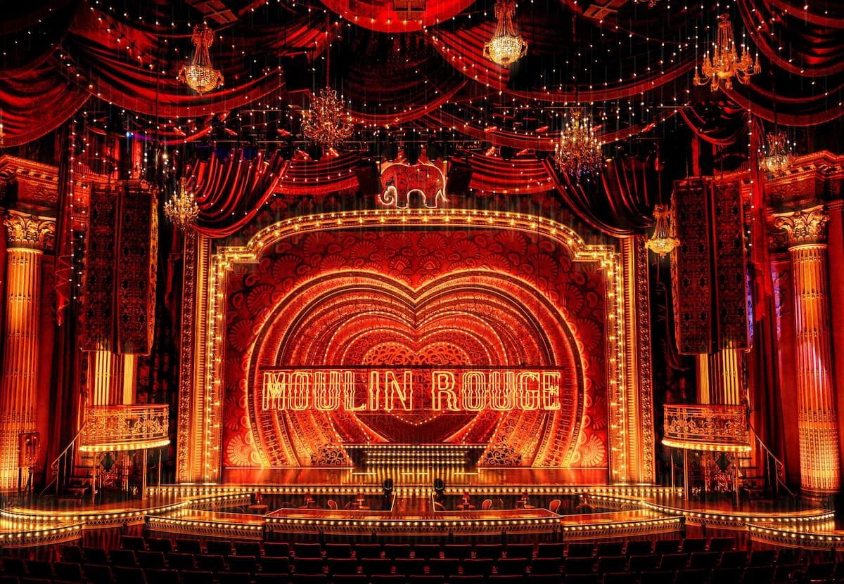 Full stage view of Moulin Rouge! The Musical dressed in Reveal's red drapery and upholstery, with chandeliers and illuminated signage